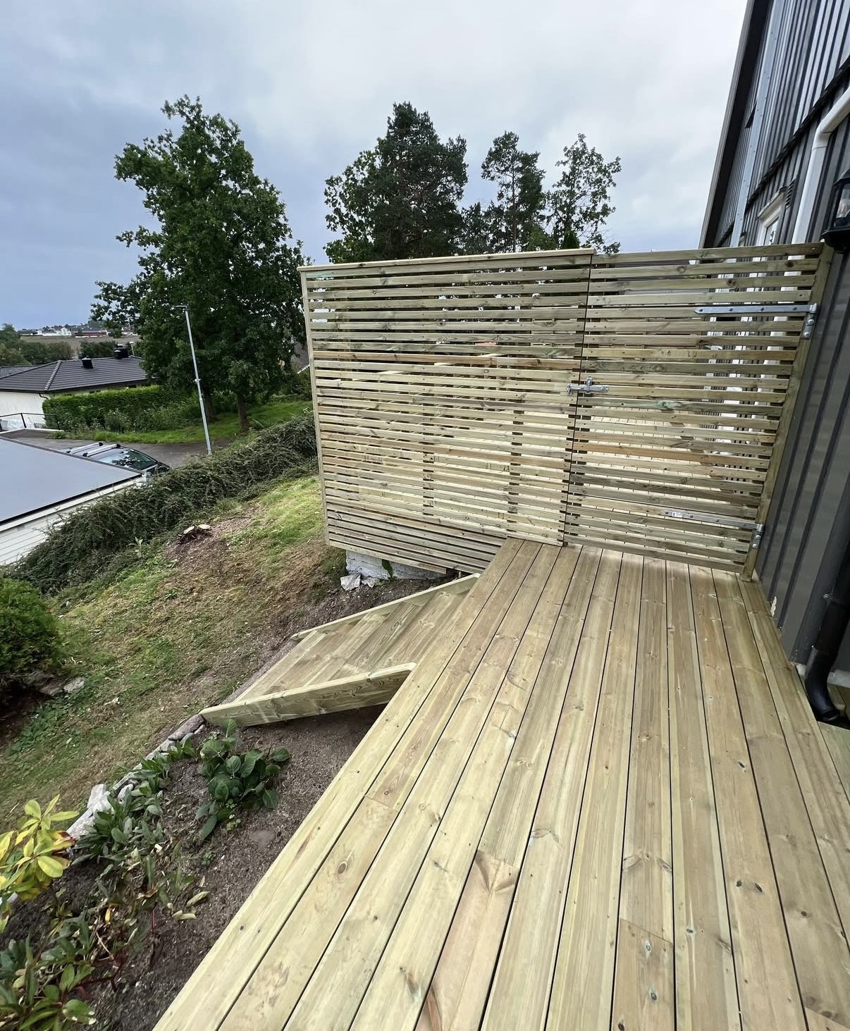 Nybygget terrasse i trykkimpregnert tre med skjermvegg og port